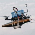A lightweight drone with an RPG warhead strapped to it using cable-ties