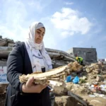 اليونسكو حنين العماسي تجمع المواد الوثائقية من أنقاض موقع دمر في غارة جوية في غزة